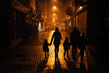 Back Of Silhouettes Family Walking In Night City.