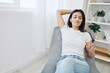 © SHOTPRIME STUDIO - Woman sitting in a chair listening to an audiobook on wireless headphones at home in jeans and a white T-shirt, fall lifestyle comfort