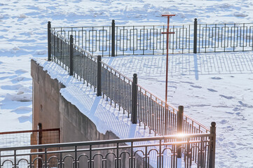 Wall Mural - The railing of the fence of the embankment of the river in the snowy winter. Sunny day. No people. View from above