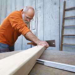 bearded man saws wooden board