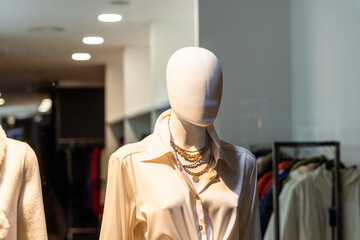  Female mannequin without a face, behind the window of a boutique