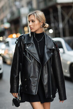 portrait of blonde woman in stylish leather jacket looking away on urban street in New York