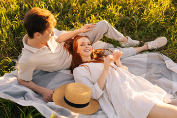 Wall Mural - high-angle view of happy redhead young woman looking at camera and lying of handsome handsome man du