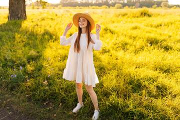 Wall Mural - full length portrait of cute smiling redhead woman in straw hat and white dress standing posing with