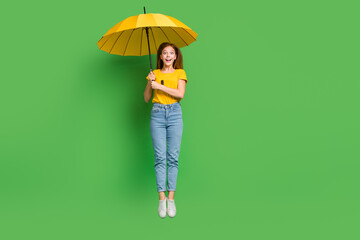 Canvas Print - Full size photo of excited cheerful girl jumping arms hold umbrella isolated on green color background