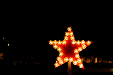 Wall Mural - Selective focus view at red star decorated sign surround the outline with line of light bulbs on dark background. 