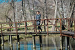 © joycedragan - Beautiful young blonde woman stands by a wooden fence on a lake in early spring