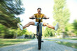 © New Africa - Handsome young man riding bicycle in city park, low angle view. Motion blur effect