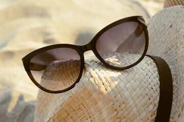 Wall Mural - Hat with beautiful sunglasses on sandy beach, closeup