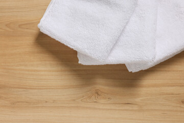 Soft folded terry towels on wooden table, top view. Space for text