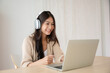 © Monster Ztudio - Young asian woman wearing headset while working on computer laptop at house. Work at home, Video conference, Video call, Student learning online class