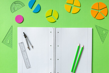 Wall Mural - School stationery, fractions, rulers, pencils on green background. Back to school, fun education concept. Set of supplies for mathematics and for school. Close up