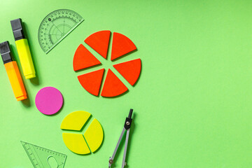 Wall Mural - School stationery, fractions, rulers, pencils on green background. Back to school, fun education concept. Set of supplies for mathematics and for school. Close up