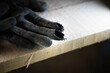 Black construction glove with rubbed fingers close-up. Holeful work gloves at a construction site on wooden scaffolding. Poor quality protective gloves torn at the fingers. Worn Builder's Equipment