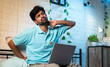 © WESTOCK - young man suffering from neck and back pain while using laptop on bed during work from home at night - concept of improper working posture, overworked and exhausted
