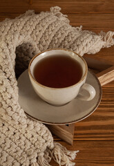 A cup of warm delicious tea on a saucer with a wooden background