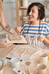 Wall Mural - Woman with apron enjoying while having a pottery class. Craft, art and hobbies concept.