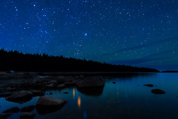 Wall Mural - night landscape with a starry sky and milky way over the water of a lake with stones