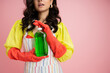 partial view of brunette woman in red rubber gloves holding green dishwashing liquid isolated on pink