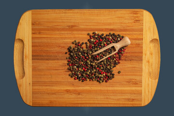 Wall Mural - Wooden food background with spices. A mixture of peppers with a wooden spoon on a kitchen board.