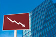 A sign showing an downward arrow in front of an office building. Concept of decreasing or slumping office rental price, demand and value or a real estate bust.