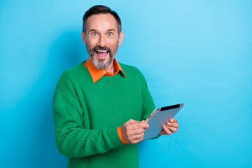 Poster - Photo of surprised shock business man wear green jumper hold tablet notepad shocked black friday cheap proposition isolated on blue color background