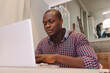 © ADDICTIVE STOCK - Black Man with a laptop on a Wooden Table