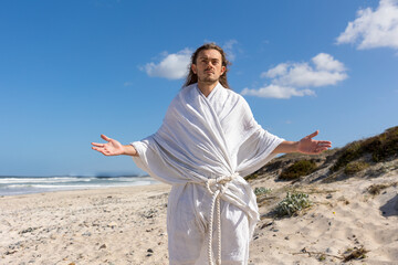 Wall Mural - Jesus-like man with open arms on beach