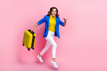 Poster - Full body profile portrait of excited lady hold suitcase jump rush hurry registration isolated on pink color background