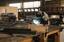 Man welding steel details using gas torch in his workshop 