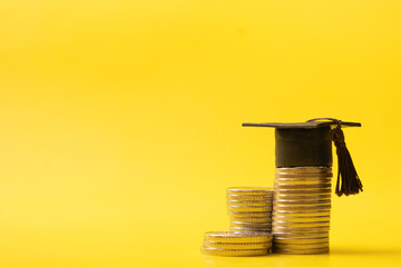 Graduated cap with coins on yellow background. Savings for education concept, back to school allowance