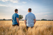 © Countrypixel - Zwei Landwirte stehen mit den Rücken zur Kamera in einem reifen Getreidefeld.