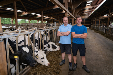 Poster - Landwirt und sein Auszubildender freuen sich auf der Diele eines modernen Rinderaufzuchtstalles über das erreichte.