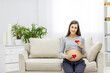 © Andrii - Photo of pregnant woman holding red heart in hands.