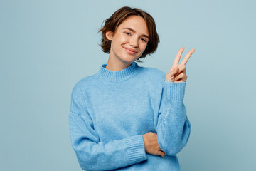 young smiling satisfied cheerful caucasian woman wear knitted sweater look camera showing victory ge