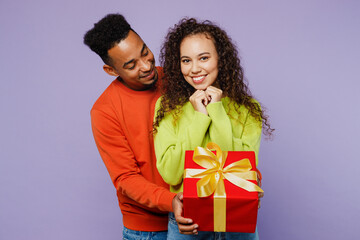 Wall Mural - Young happy couple two friends family man woman of African American ethnicity wear casual clothes together give red present box with gift ribbon bow isolated on pastel plain light purple background.