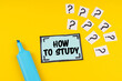 On the yellow surface is a marker, question marks and a sticker with the inscription - HOW TO STUDY