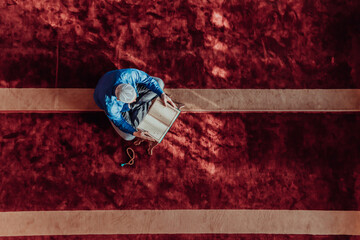 Wall Mural - A Muslim reads the holy Islamic book Quraqn in a modern grand mosque during the Muslim holy month of Ranazan