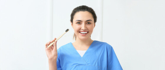 Canvas Print - Female dentist with toothbrush on light background