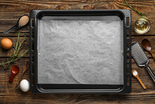 Baking Tray With Paper, Kitchen Supplies And Ingredients On Dark Wooden Background