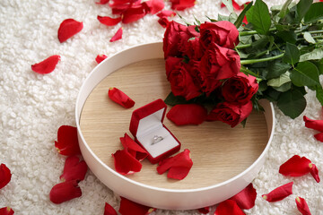 Tray with engagement ring and roses on bed in room decorated for Valentine's Day, closeup