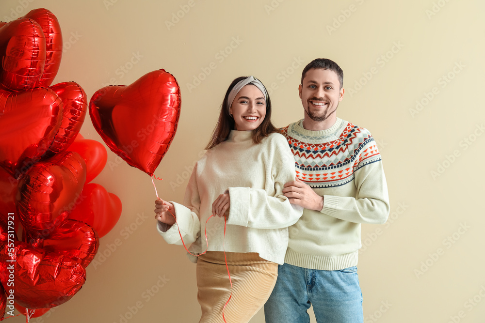 Happy couple in love with balloons on beige background. Valentine's Day celebration