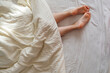 © phpetrunina14 - A woman's legs stick out from under her blanket