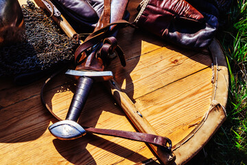 Medieval sword and chain mail lie on a wooden shield. Close-up