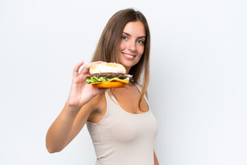 Wall Mural - Young pretty woman holding a burger isolated on white background with happy expression