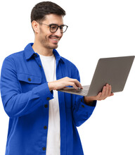 Young Man Wearing Casual Blue Shirt, Standing With Opened Laptop In Hands, Surfing Online