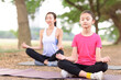 © Tom Wang - Mother and daughter doing yoga exercises on grass in the park