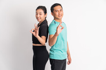 smiling asian woman and man standing back to back with okay gesture on isolated background