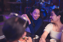 Two Southeast Asian Ladies Smile At Each Other As They Catch Up In A Get-together Dinner. Long-term Bestfriends Bonding Over Supper. Eye Contact Between Two Chatty Friends.