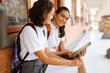 © Odua Images - Asian high school student smiling while using a pad while sitting outside the classroom